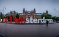 Unidentified Tourist at the red and white I am Amsterdam sign in center of Amsterdam