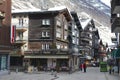 Unidentified tourists explore traditional wooden houses street in Zermatt, Switzerland.