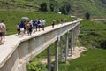 Unidentified tourists and locals cross concrete bridge