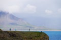 Unidentified tourists standing at the cliff near Gatklettur Stone Arch, Iceland