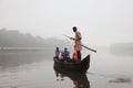 Villagers travel by a ferry boat to cross the river Pamba in a foggy morning