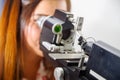 Unidentified woman checks vision by modern equipment, eyes exam in optical, in a blurred background