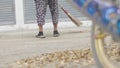 Unidentified woman sweeping the leaves with broom in the park.