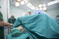 An unidentified woman are undergoing cesarean delivery by a medical team