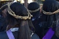 Unidentified Women penitents in garb and crown of bitter herbs carrying angel figurine scepter standing on the churchyard on Lente