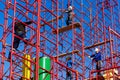 Unidentified workers setting up iron scaffolding at construction