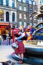 Unidentified young man with a bagpipe in the Scottish national dress at Piccadilly Circus