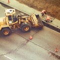 Uniform workers remove asphalt by folding it into an excavator bucket