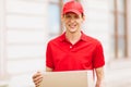 A uniformed courier holds an empty cardboard box in the open air. Delivery service