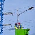 Uniformed electricians repairing electrical wires on a high pole - Moscow, Russia, September 26, 2020