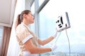 A uniformed maid installs a window cleaner robot on the glass. Clean windows. Photos in the interior. The concept of