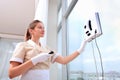 A uniformed maid installs a window cleaner robot on the glass. Clear window. Photos in the interior. The concept of