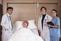 Uniformed professional doctors with male patient in inpatient room of hospital Royalty Free Stock Photo