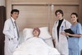 Uniformed professional doctors with male patient in inpatient room of hospital Royalty Free Stock Photo