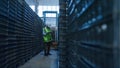 Uniformed warehouse worker checking boxes shipment counting blue packages