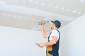 A uniformed worker applies putty to the drywall ceiling. Putty of joints of drywall sheets