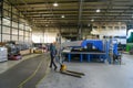 uniformed worker pulls a forklift cart in an industrial warehouse, wears a mask on his face due to a coronavirus