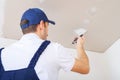 A uniformed worker puts putty on the caps of the screws on the ceiling made of drywall sheets Royalty Free Stock Photo