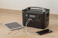 Uninterruptible power supply source. Portable power station charching tablet and smartphone Royalty Free Stock Photo