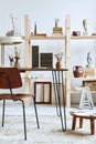 Unique artist workspace interior with stylish desk, wooden easel, bookcase, artworks, painting accessories, decoration.