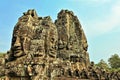 The unique Bayon temple. Against the blue sky towers with gigantic faces carved from stone rise