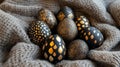 Unique black and gold patterned decorative eggs resting on a cozy gray textile in a warm indoor setting Royalty Free Stock Photo