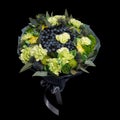 Unique bouquet consisting of blueberries, blackberries, lemons decorated with green carnations is isolated on a black background a