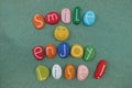 Smile and enjoy life, creative phrase composition with multi colored stones over green sand Royalty Free Stock Photo