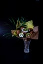 Unique festive bouquet of coconut, kiwi and palm twigs on a black background. Fruit bouquet. Fruits and Vegetables of the Healthy