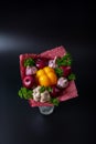 Unique festive bouquet of yellow peppers, red onions, garlic, mushrooms and parsley on a black background. Vegetable bouquet