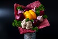 Unique festive bouquet of yellow peppers, red onions, garlic, mushrooms and parsley on a black background. Vegetable bouquet