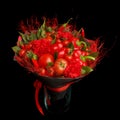 Unique gift handmade in the form of a bouquet consisting of a tomatoes, red peppers, bay leaves standing in a vase on a black back