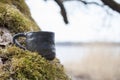 Unique handmade cup with folk sign on moss with blurred lake on background Royalty Free Stock Photo