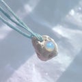 A Unique Handmade Pendant Featuring an Iridescent Opal Gemstone Encased in a Soft Clay Material, Perfect for Adding a Royalty Free Stock Photo