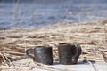 Unique handmade two cups with folk sign with blurred lake on background Royalty Free Stock Photo