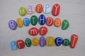 Happy Birthday Mister President with colored stones over white sand