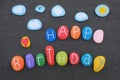 Creative Happy Birthday text with colored and carved sea stones over black volcanic sand Royalty Free Stock Photo
