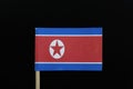 A unique and official flag of North Korea on toothpick on black background. A wide red stripe at the center, bordered by a narrow