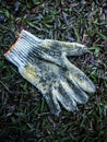 Unique photo shot of used gloves of construction workers in grass dark gradation background