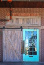 Unique rustic barn door entrance to building with reflection of nature in one side with glass panes all set in brick with red Royalty Free Stock Photo