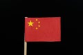 A unique and simply flag of China on toothpick on black background. A large golden star within an arc of four smaller golden stars