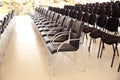 Uniqueness concept. Rows of black folding chairs empty in a conference room . Unique throne or ceremonial armchair with seat and Royalty Free Stock Photo