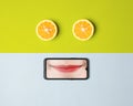Unique wallpaper concept combining a fresh orange cut and smartphone image with lovely smiling lips.