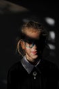 Unique young caucasian person wunderkind little girl in glasses and school black and white uniform smiling in darkness