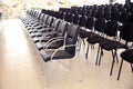 Uniqueness concept. Rows of black folding chairs empty in a conference room . Unique throne or ceremonial armchair with seat and Royalty Free Stock Photo