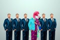 Uniqueness creative background, among the crowd of businessmen multicolored freak flamingo. Competitive advantage, standing out Royalty Free Stock Photo