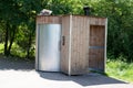 Unisex public dry toilet modern wooden outhouse outside in park Royalty Free Stock Photo