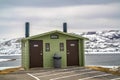 Unisex public restroom against lake snowy mountain and cloudy sky in winter Royalty Free Stock Photo