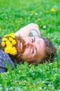 Unite with nature concept. Bearded man with dandelion flowers lay on meadow, grass background. Man with beard on smiling Royalty Free Stock Photo