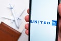 United Airline app on a smartphone screen with a plane and passport on the background. The concept of travel app